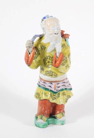 A 19thC Chinese polychrome porcelain figure of a bearded sage, dressed in a yellow robe, 27cm high.