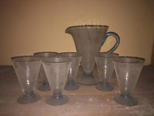 A 1930's glass lemonade set, comprising six tapered crazed conical glasses with blue feet and a jug to match with applied blue handle.