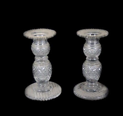 A pair of Regency cut glass candlesticks, with double knopped and ring stems, with hobnail cut decoration, raised on circular stepped feet with hobnail cut bases, lacking lustre drops, 17cm high.