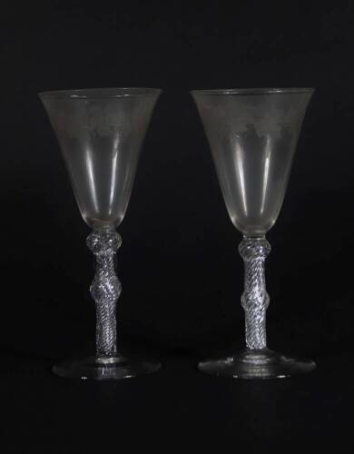 A pair of early 19thC wine glasses with trumpet shaped bowls, each engraved with a band of fruiting vine decoration, on double knopped air twist stems, and plain circular feet, 18.5cm high.