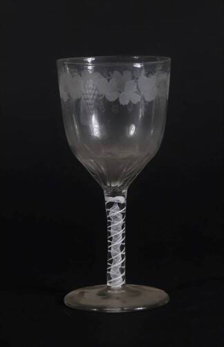 A 18thC glass wine goblet, with semi fluted bowl engraved with a band of fruiting vine decoration, and with an opaque twisted stem, on a plain circular foot, 18cm high.