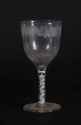 A 18thC glass wine goblet, with semi fluted bowl engraved with a band of fruiting vine decoration, and with an opaque twisted stem, on a plain circular foot, 18cm high.