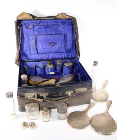 A collection of silver backed ladies dressing table accoutrements, including three hand mirrors, three hair brushes, two clothes brushes and twelve various silver lidded toilet jars, various dates and makers (some matching), etc., all contained within a f