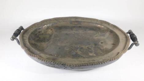 A Victorian oval silver plated hot water meat dish, with shaped gadrooned border and turned ebony handles, raised on four bun feet, 55cm.