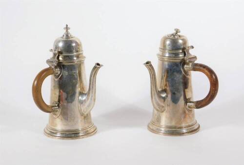 A pair of Edwardian silver chocolate pots, reproduced in the early Georgian manner with hinged lids, tapered bodies and octagonal tapered spouts, London 1907, makers: Alexander Clarke & Co, 18cm high, 18oz all in.