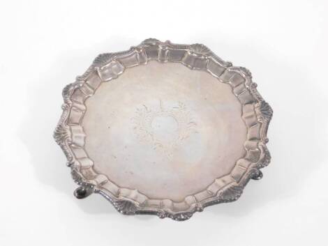 An early George III circular silver salver, with Chippendale raised moulded border and engraved central foliate scroll cartouche, raised on three stylized hoof feet, London 1760, makers mark indistinct either BP or RP; 19cm diameter, 11oz.