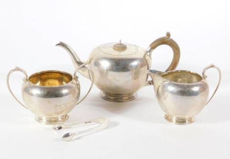 A George V silver three piece tea set, of plain swollen design, London 1919, makers: Goldsmiths and Silversmiths Company, 25oz all in, and a pair of silver sugar bows. (4)