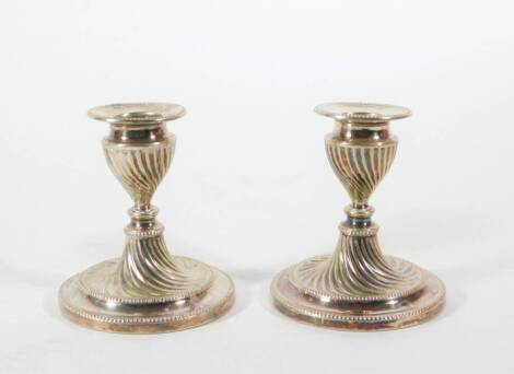 A pair of silver plated dwarf candlesticks, of classical urn shaped whorl fluted design, marked H E & Co, 10cm long.