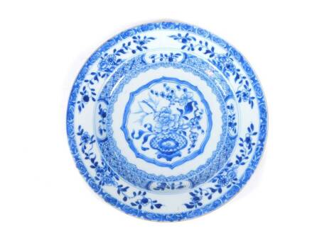 An 18thC Chinese blue and white plate, decorated with a stylized vase of flowers and cell border, 23cm diameter.