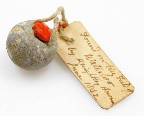 A lead musket ball from the battle field of Waterloo, which bears a label attached by red sealing wax and states: 'found on the field of Waterloo by Knightley Howman, June 1842'.