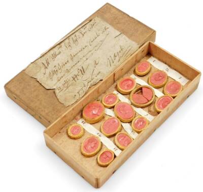 A collection of 18thC Grand Tour coral plaster cameos, depicting classical Roman figures, etc., contained in the original wooden box with a hand written inscription in Italian on paper applied to the lid.