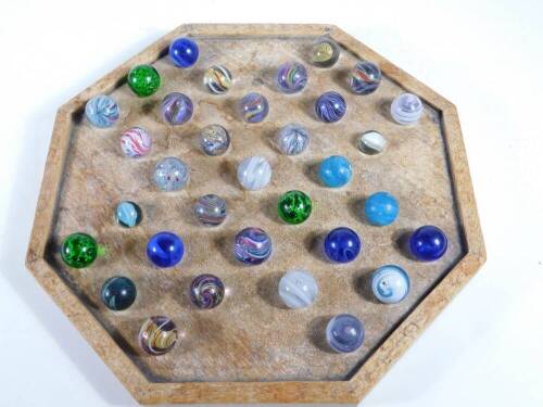 An octagonal solitaire board and a collection of marbles.