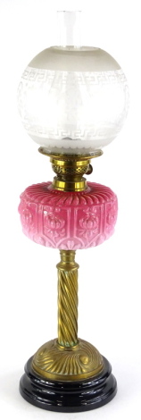A Victorian brass oil lamp, with a frosted globular stencilled shade, a brass fitting stamped British Made, and a pink tinted moulded glass reservoir on a wrythern column and ceramic base, 69cm high.