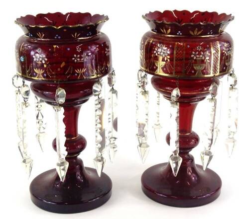 A pair of 19thC ruby tinted glass table lustres, each decorated with gilt vases with flowers, etc., picked out in raised turquoise and white enamel, on a shaped column and foot, 33cm high.