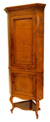 A 19thC oak and burr oak standing corner cabinet, with a moulded and dental cornice above a panelled door enclosing three shelves, and the base with a further panelled door enclosing a recess on cabriole legs with under tier, 201cm high, 78cm wide.