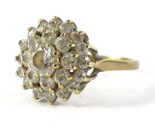 A cubic zirconia dress ring, with layered arrangement of stones, with central stone surrounded by two rows of smaller stones, yellow metal, indistinctly marked, 3.1g all in.