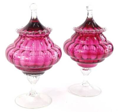 A pair of Victorian style cranberry tinted and clear glass bon bon dishes, each with a tapering lid, a baluster shaped stem and a domed foot, 34cm high.