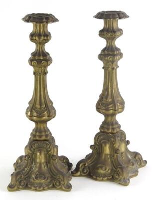 A pair of continental brass candlesticks, each decorated in rococo style with scrolls, shells, etc., 40cm high.