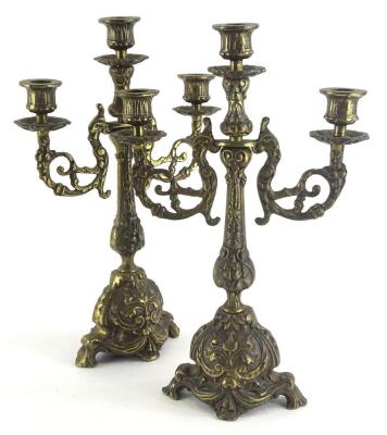 A pair of continental cast brass three branch candelabra, each decorated in rococo style, 35cm high.