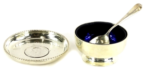 An Indian white metal trinket dish, inset with a 1915 one rupee coin, marked silver to under side, and a silver plated salt, with blue glass liner and spoon, weighable silver 1½ oz.