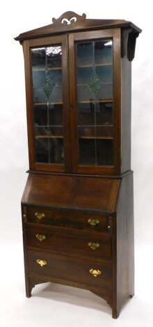 An Edwardian mahogany bureau bookcase, the top with a pierced crest, above two leaded glazed doors with inset stained glass lozenges, the base with a fall enclosing a plainly fitted interior above three drawers on bracket feet, 76cm wide.