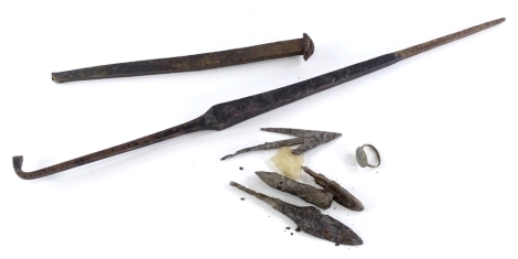 A collection of excavated artifacts, to include metal arrow heads, a flint arrowhead, a large iron nail and a copper or bronze dagger or implement.