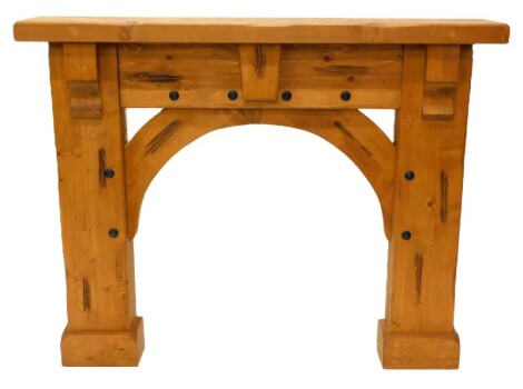 A heavy rustic pine fire surround, with decorative hammered metal roundels, 120cm high, 152cm wide, 28cm deep.