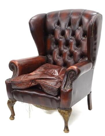 A mahogany wing back chair in George III style, upholstered in red leather on cabriole legs.