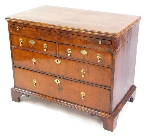 A William & Mary and later walnut bachelor's chest, of two short over two long drawers, with brushing slide and feathered cross banding, with a quarter veneered top, raised on bracket feet, 76cm high, 73.5cm wide, 53.5cm deep.