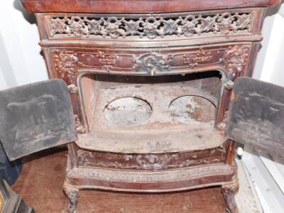 A French late 19thC cast iron and enamel wood burning stove Le Vosgien, No 258, by De Dietrich & Cie., Niederbronn., of serpentine form, the front and sides with a pierced grill moulded with cherubs' heads, the two doors and side panels moulded with castl - 3