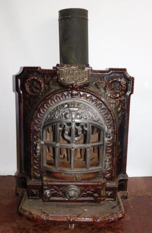 A French late 19thC cast iron and brown enamel Gallia stove, of bow fronted form, embossed with laurel wreaths and flaming torch, raised on a shaped hearth, 66cm high, 56cm wide, 43cm deep.