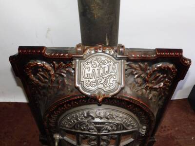 A French late 19thC cast iron and brown enamel Gallia stove, of bow fronted form, embossed with laurel wreaths and flaming torch, raised on a shaped hearth, 66cm high, 56cm wide, 43cm deep. - 2