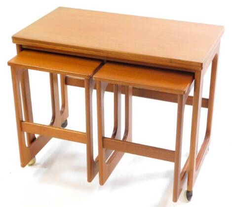 A McIntosh triform nest of occasional tables, the largest with a fold over top, raised on shaped end supports united by a stretcher, on castors, holding two similar smaller tables, largest table 61cm high, 74cm wide, 40cm deep, 80cm extended.