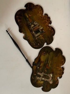 A pair of Victorian papier mache hand screens, of shaped design and mother of pearl inlay, depicting scenes of a castle and ruins, one turned ebony handle only, detached. (AF)