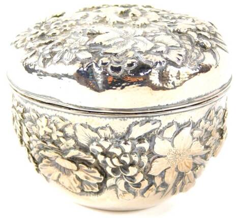 A Chinese cylindrical silver box and cover, repousse decorated with mixed flowers, four character mark, 6.56 oz, 9cm diameter.