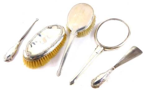 A George V silver backed hair brush and hand mirror, with engine turned and floral engraved decoration, Birmingham 1920, further hair brush, embossed with flowers, initial engraved, Birmingham 1920, and a shoe horn and button hook, with silver handles, em