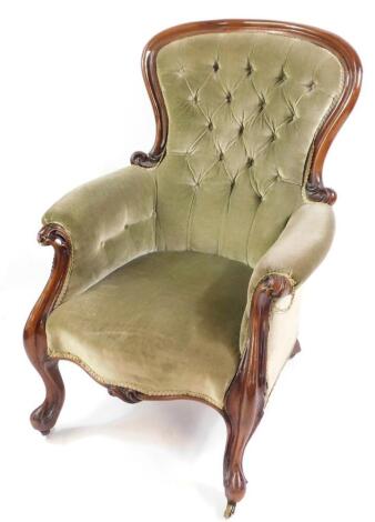 A Victorian mahogany spoon back nursing chair, upholstered in green button back fabric, raised on cabriole legs on castors.