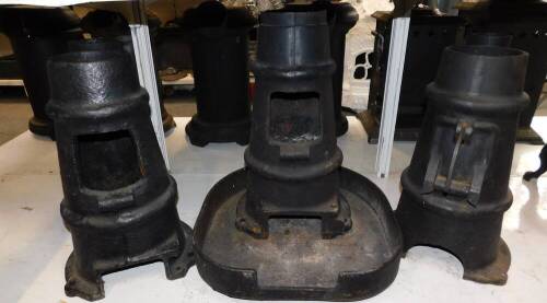 Three cast iron multi fuel burners, of chimney form, one with a base stand, 48cm high. (4)