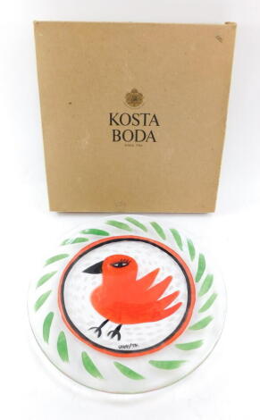 A Kosta Boda Somebody glass dish, designed by Ulrica Hydman-Vallien, painted with a red bird within a repeating leaf border, no 79600, painted mark, boxed, 33cm wide.