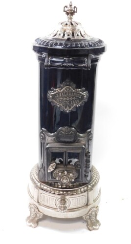 A St Joseph Couvin Le Salamandre stove, cast iron, polished white metal and black enamel, of cylindrical form, the domed cover with urn finial, drop down heat release and burner door with screw adjustment, over an ashes drawer, raised on four scroll feet,