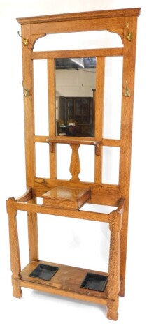 A Victorian oak hall stand, with a mirrored back and coat hooks, central hinged glove box, over a double recessed stick and brolly stand with metal drip trays, raised on shaped legs, 187cm high, 80cm wide.