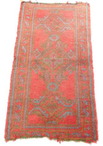 A Caucasian rug, red ground decorated with three central medallions within geometric borders, 165cm x 90cm.