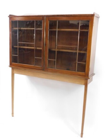 A mahogany display cabinet on stand, with a pair of astragal glazed doors opening to reveal two shelves, on a later teak console table base, raised on tapering square legs and spade feet, 173cm high, 135cm wide, 31.5cm deep. (AF)