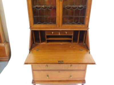 A Victorian Arts & Crafts style light oak bureau bookcase, the beaded pediment above a pair of glazed doors enclosing three shelves, fall flap opening to reveal two short drawers and six recesses above two short over two long drawers raised on cabriole le - 2