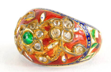 An Indian enamel and gem set ring, the ring set with central cabochon green emerald, in a floral cluster set with various old cut diamonds, in red, blue and white enamel, on a yellow metal band, unmarked, the enamel AF, ring size K½, 6.4g all in.