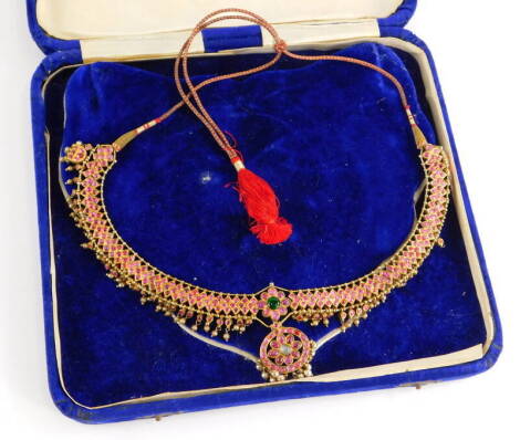 An Indian dress necklace, the necklace set with cabochon set rubies, with emerald and moon stone centre, with cultured pearl pendant surround, on a plain gold coloured back, possibly silver gilt, on a red and gold string necklace, 22cm wide approx, 45.3g 