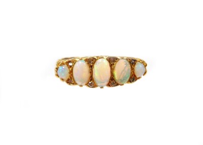 A Victorian 18ct gold opal and diamond gypsy ring, set with five oval opals and eight tiny diamonds, in a scroll design shoulders, London 1929, ring size 'R', 6.9g all in.