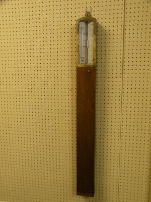 An Edwardian oak and brass stick barometer with ivorine thermometer etc