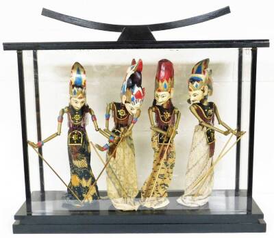 An Eastern glass display case with four puppet figures, each in floral dress with sequin bordering, 72cm high, 93cm wide, 29cm deep.