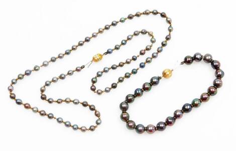 A blackened pearl single strand necklace and bracelet set, on a yellow metal ball clasp stamped 750, 55cm long overall, the natural dark and pearl bracelet with 18 carat gold a ball clasp, 19cm long overall. (2)